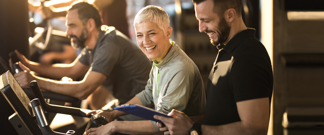 Woman on fitness equipment interacting with her personal trainer