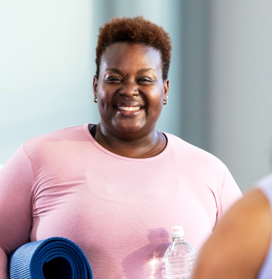 Woman smiling with yoga mat and water bottle