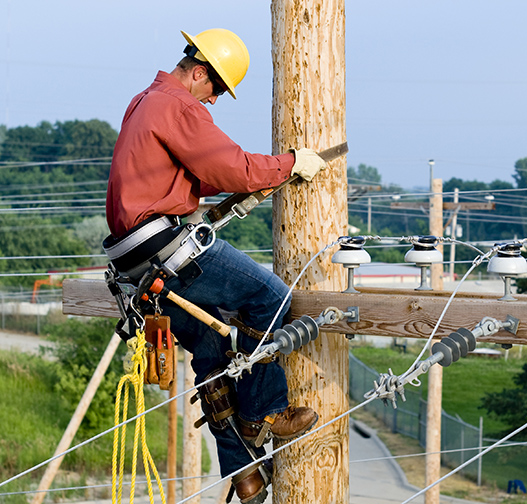 Utility worker climbing electrical pole.