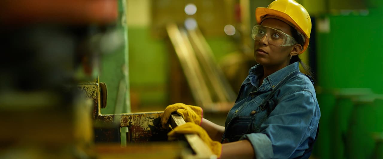 Worker in a industrial space wearing a hard hat, safety glasses and gloves