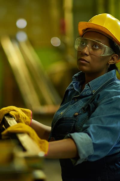 Worker in a industrial space wearing a hard hat, safety glasses and gloves