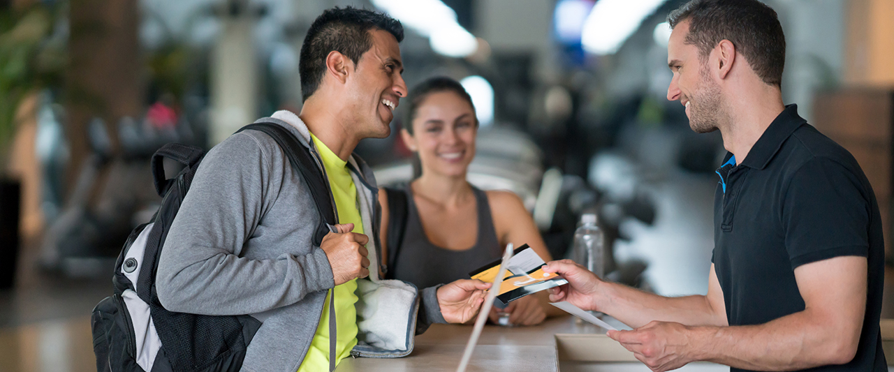 Fitness members checking in at a desk with attendant