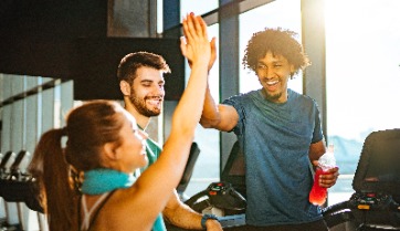 3 friends high five at corporate fitness center